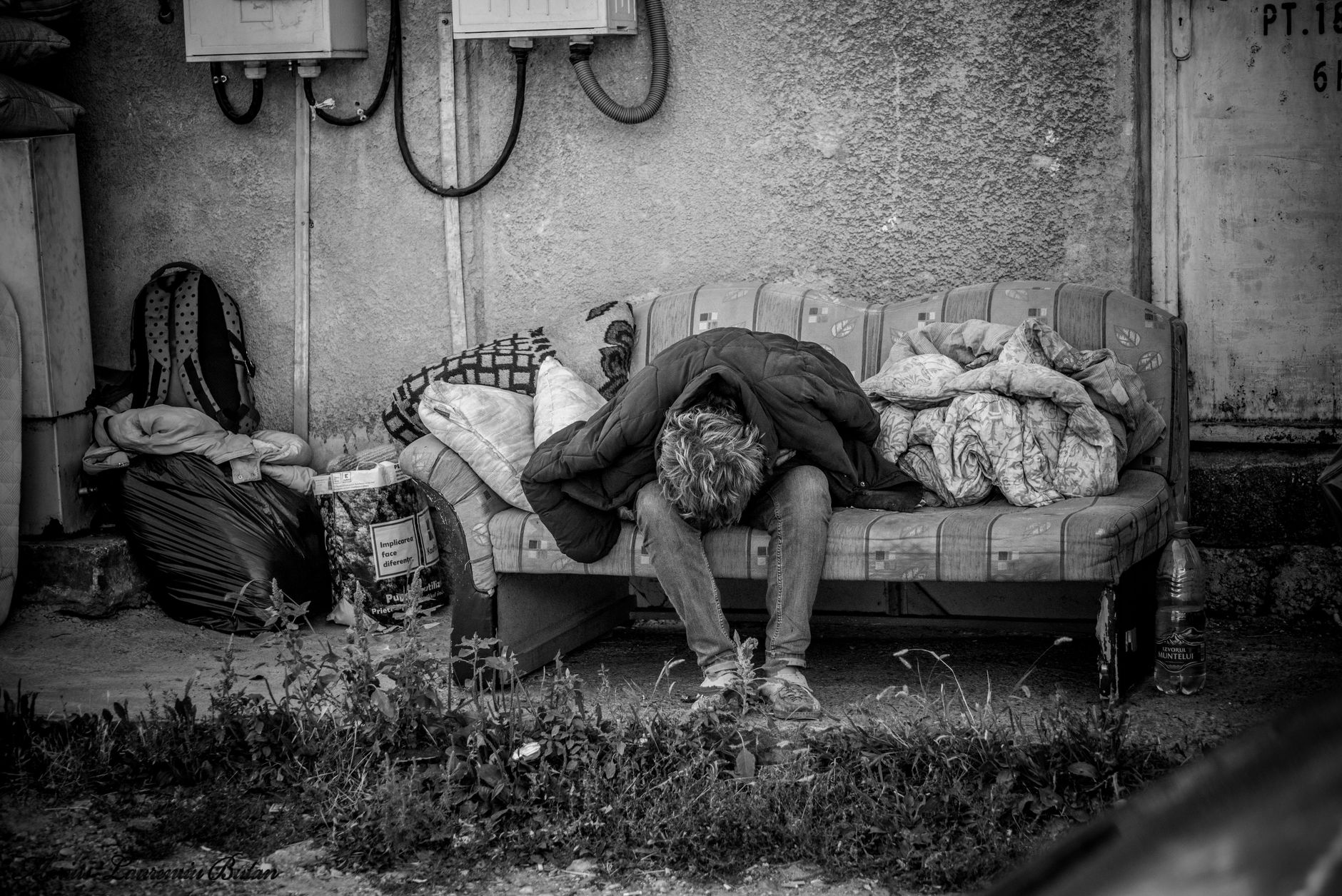 Young woman sitting on sofa with belongings in bags - depicting hidden homelessness scenario