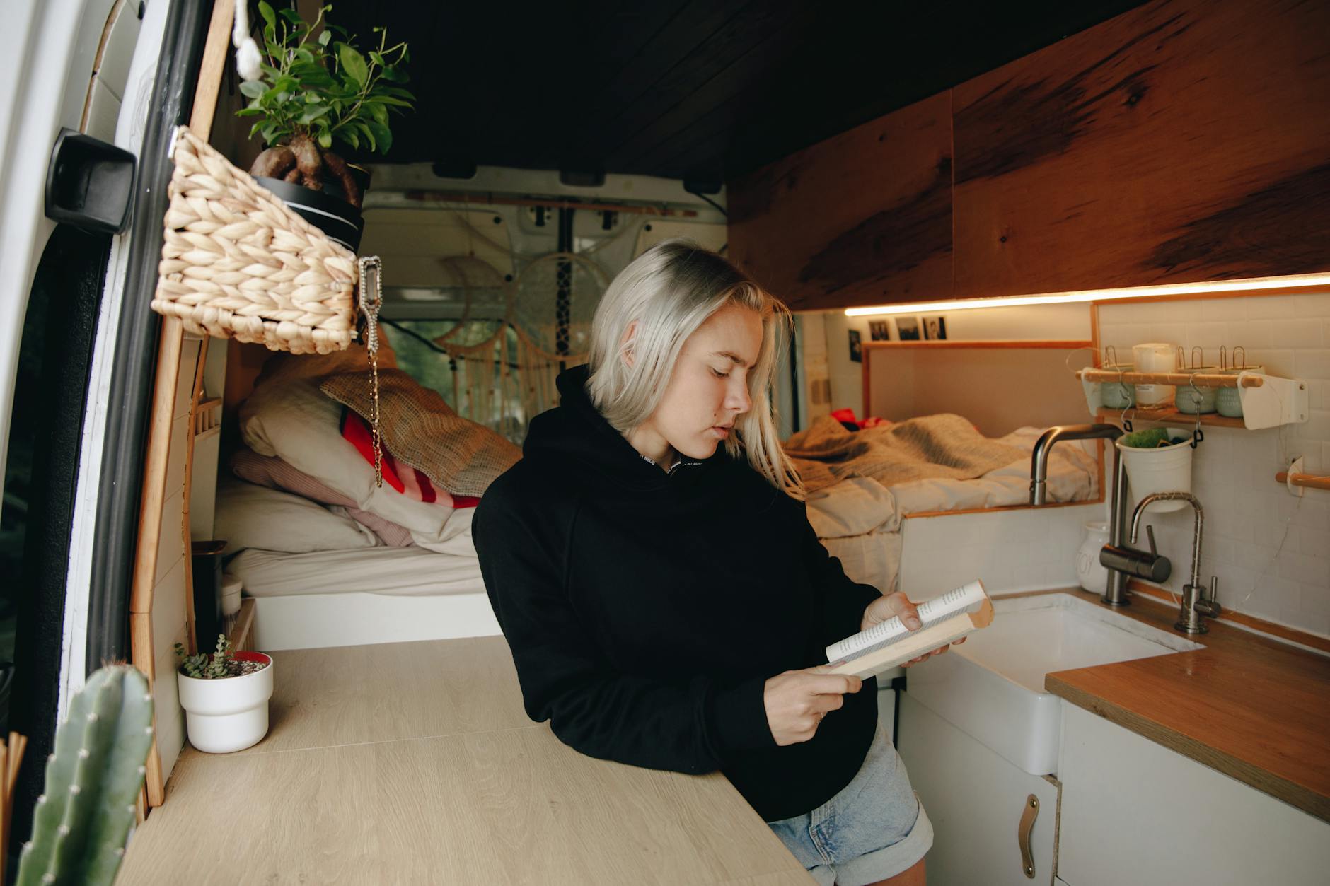 Young person converting a van into a living space with bedding and storage