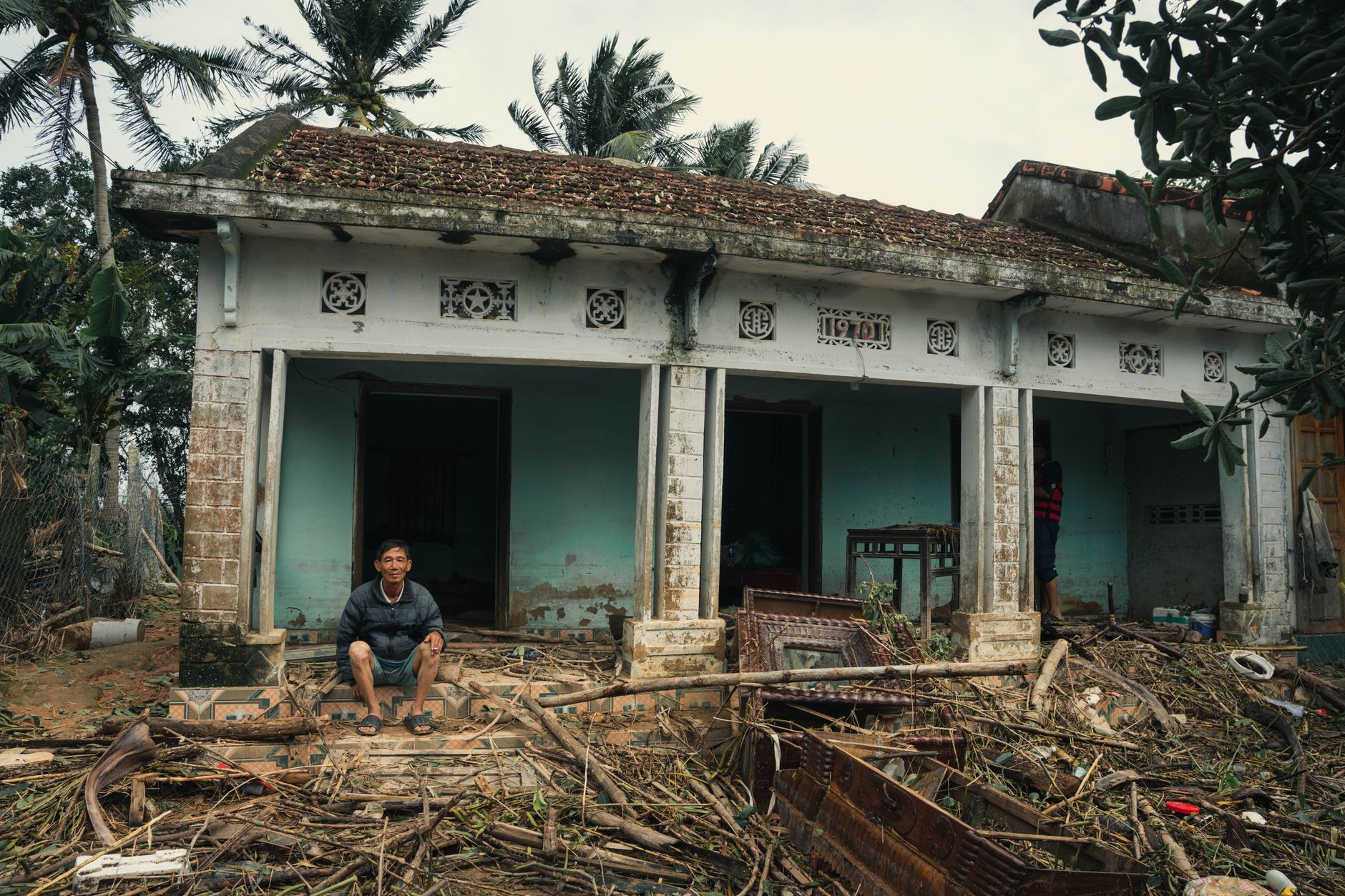  A distressed man sitting on a suitcase outside a boarded-up house