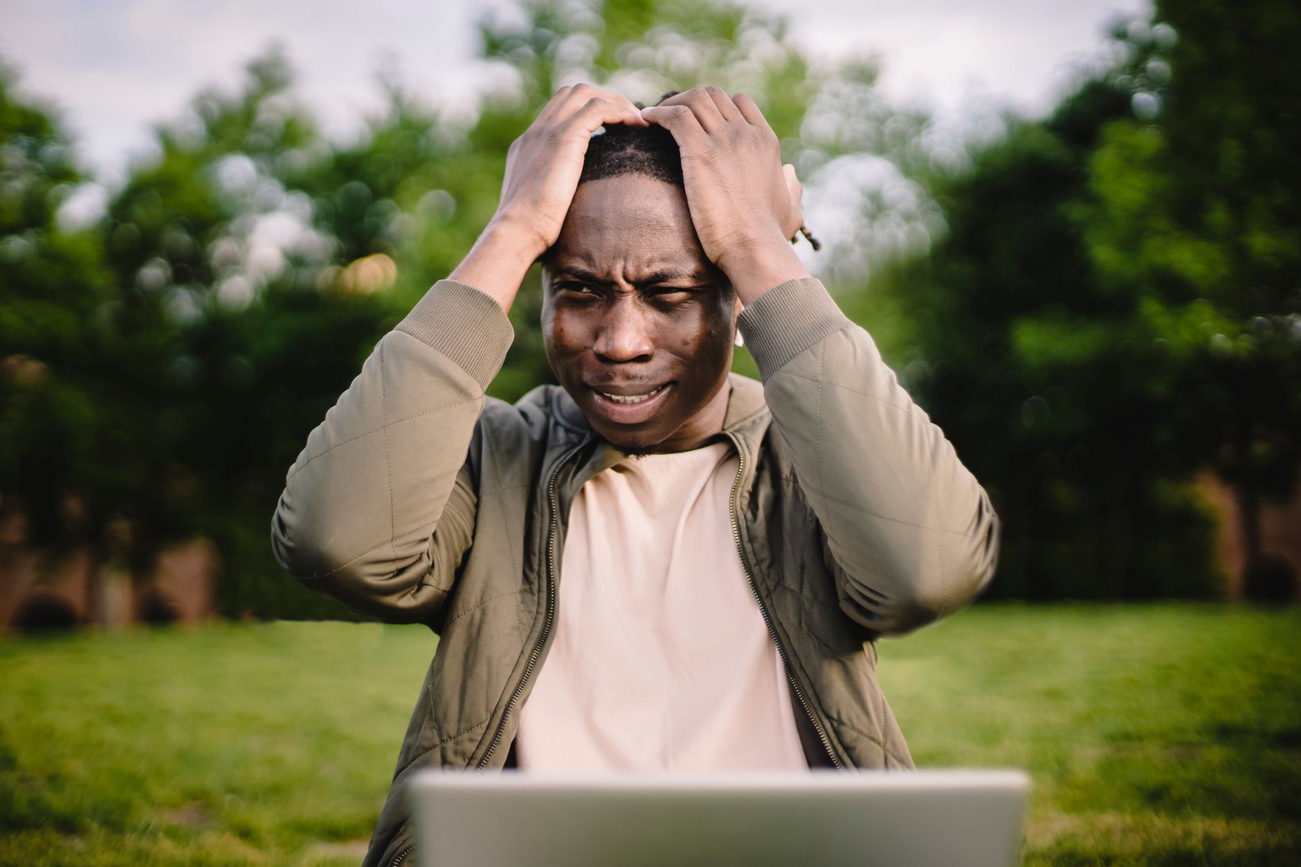 A young professional looking frustrated while browsing property listings on a laptop
