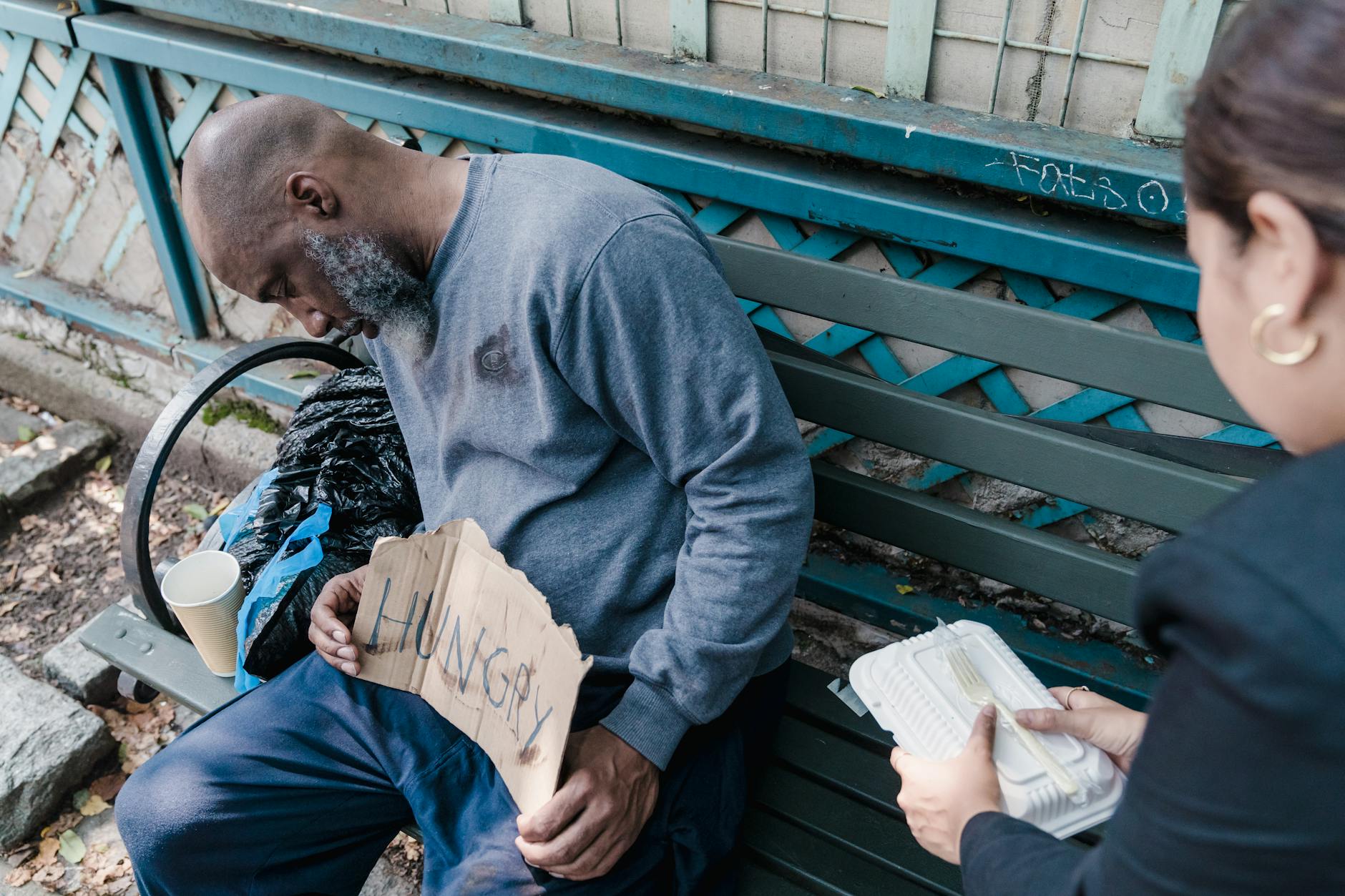  Homeless person sleeping rough in urban setting with a concerned outreach worker offering help