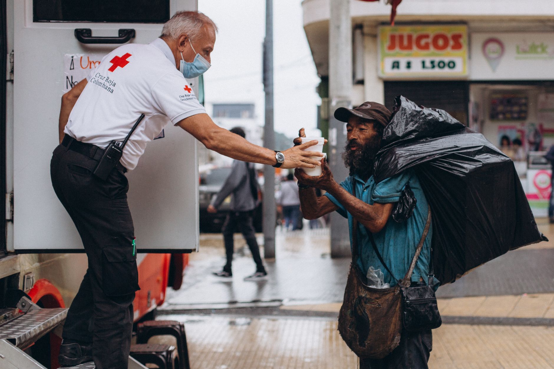 Volunteer handing water bottle to homeless person in hot weather - showing community support during heatwaves