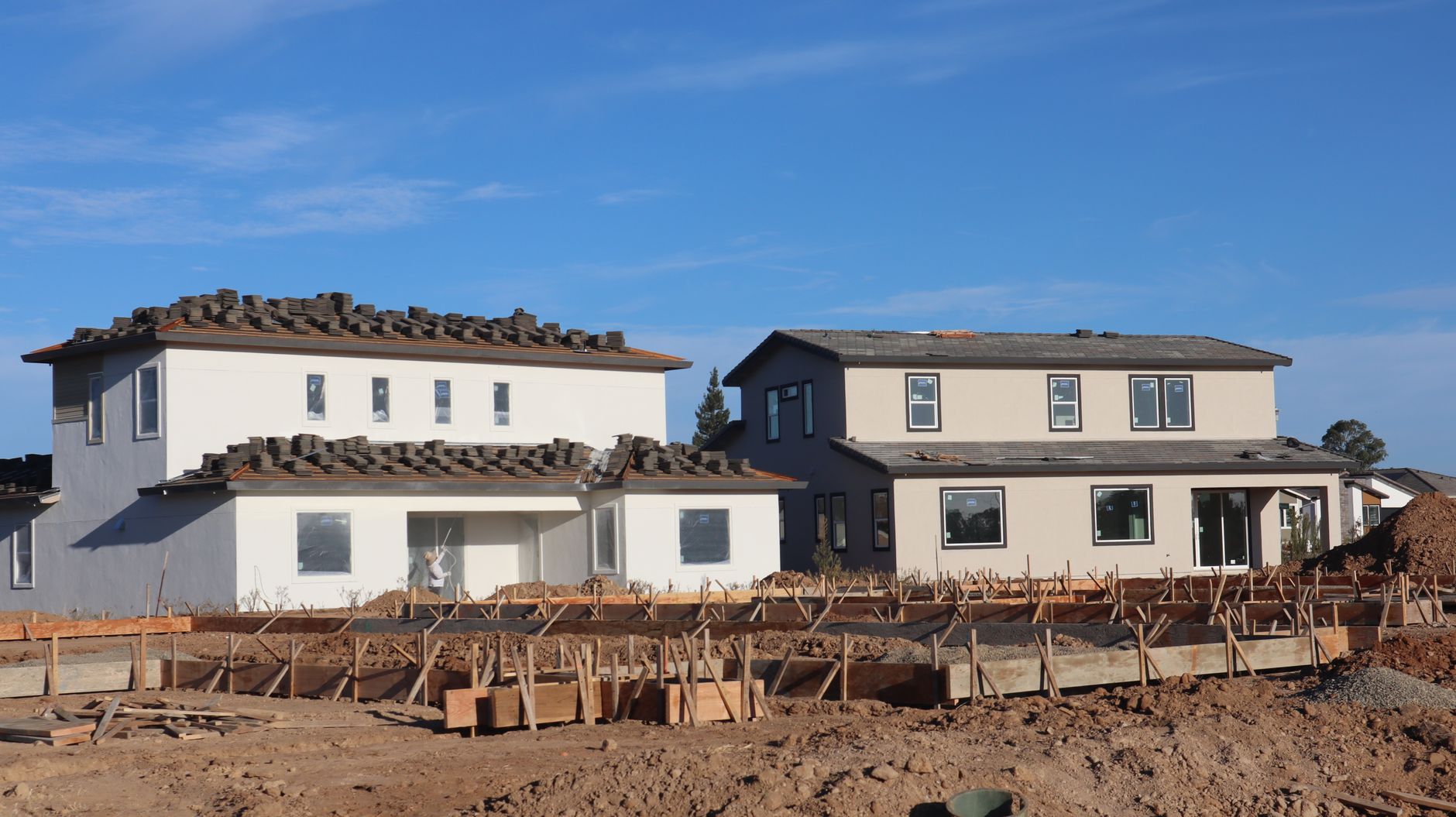 Social housing developer construction site with families walking past completed homes, illustrating the intersection of affordable housing and property access initiatives