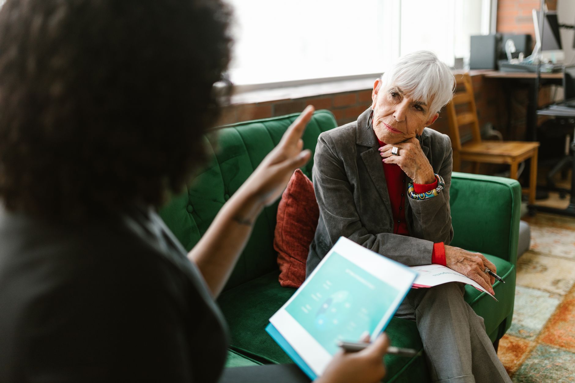 Housing officer speaking with an elderly resident in a communal lounge